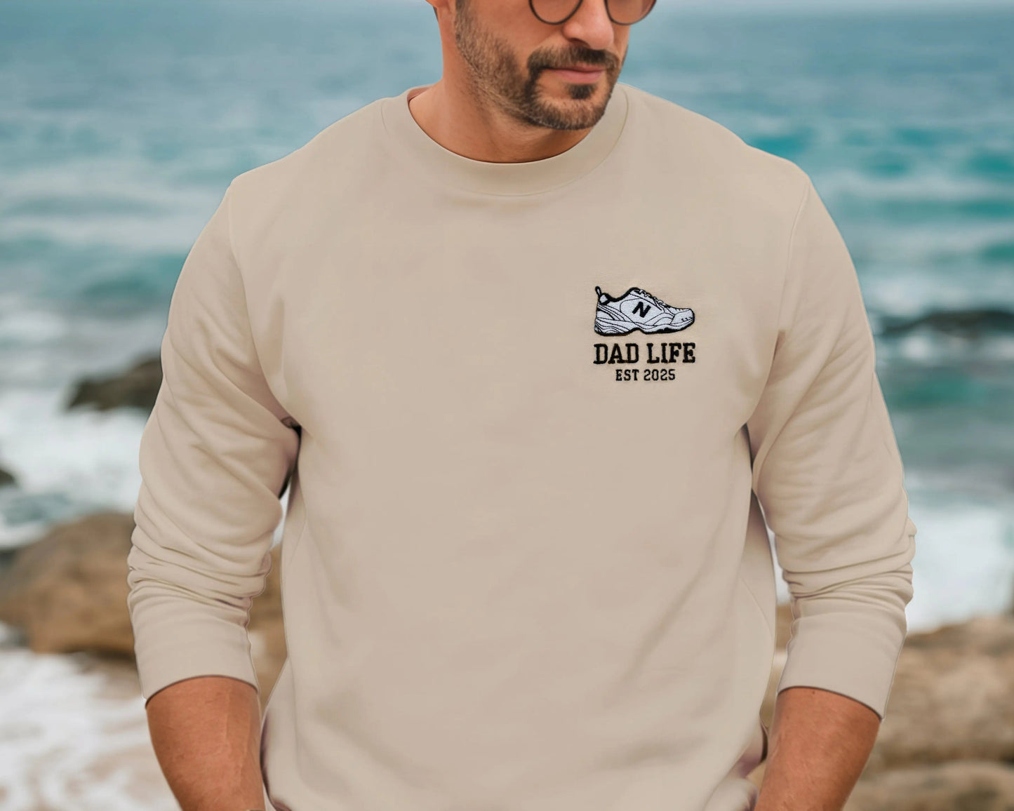 Beige dad life sweatshirt embroidered with new balance dad sneaker and est year. Best gift for new dads on model outside