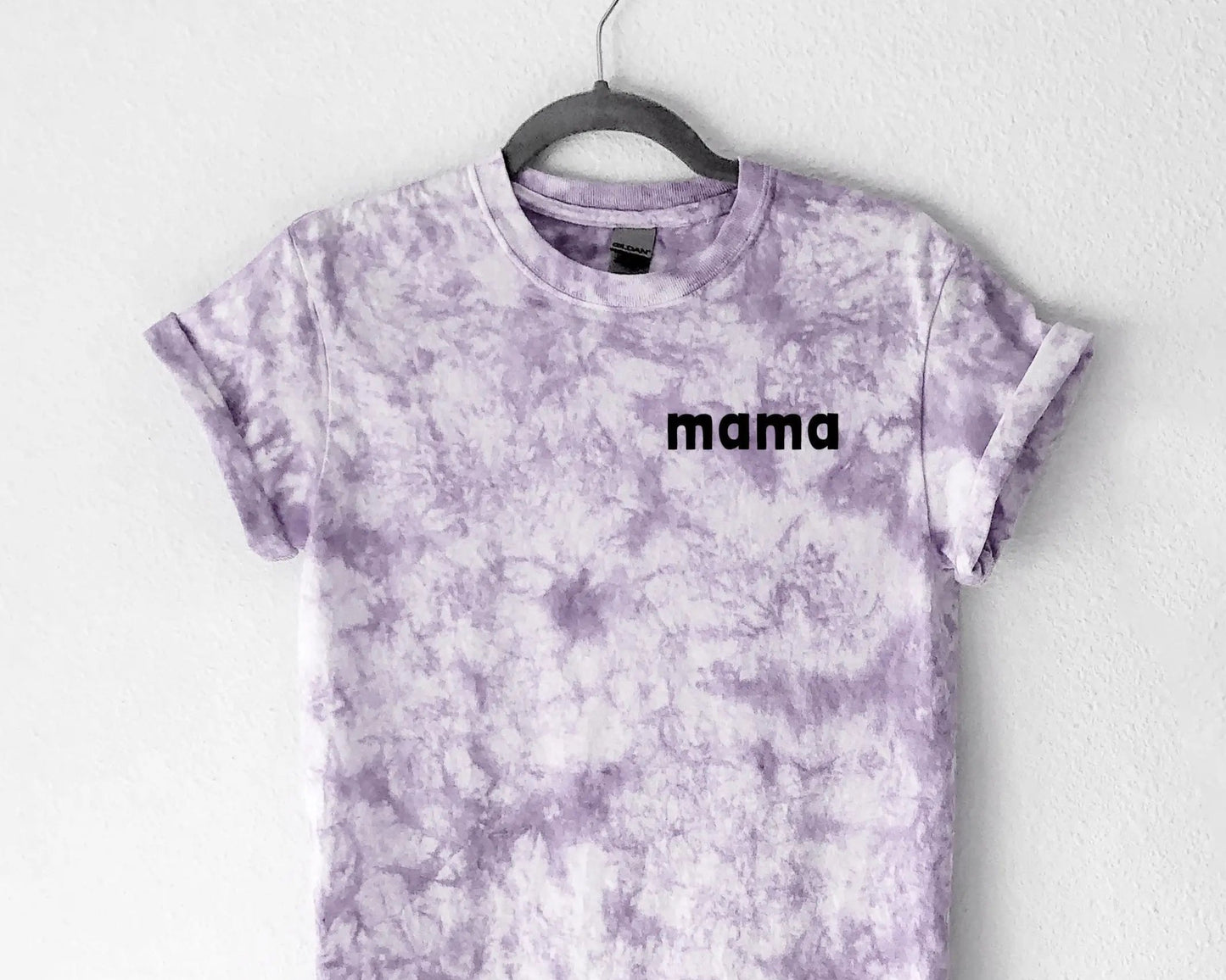 Tie-dye t-shirt with 'mama' text on a hanger against a white background