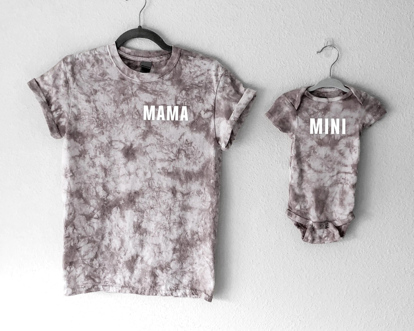 Tie-dye t-shirt and baby onesie with 'MAMA' and 'MINI' text on a white background