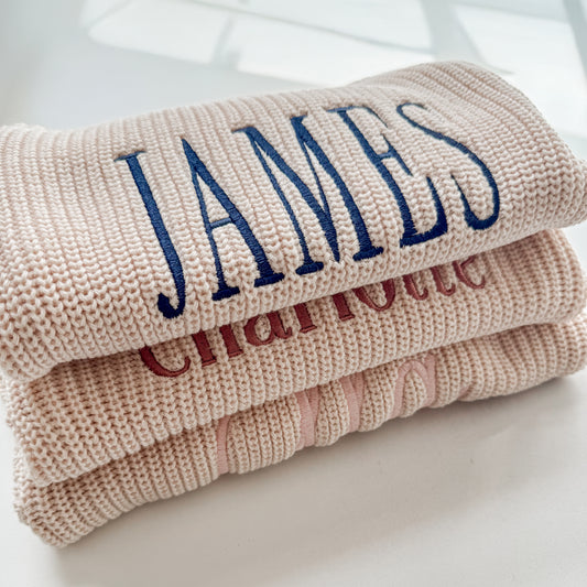 Custom baby name sweater romper made from soft beige cotton knit fabric with embroidered lettering