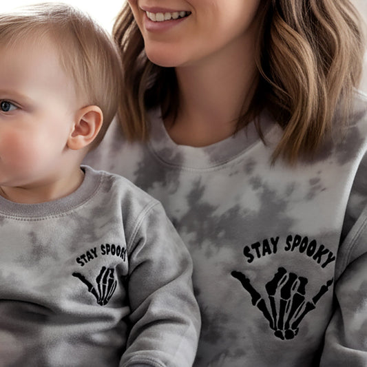 Woman and child wearing matching tie-dye sweatshirts with 'Stay Spooky' design.