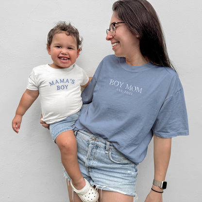 Woman holding a child wearing t-shirts with text against a plain background
