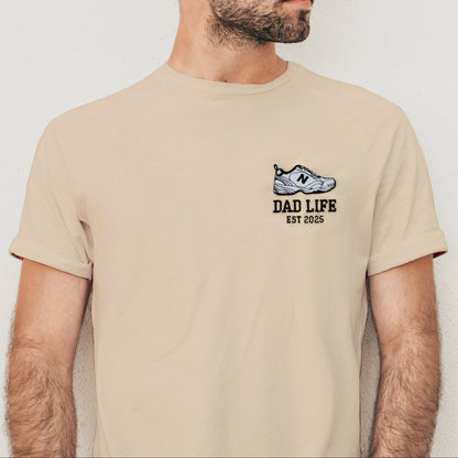 Man wearing a beige t-shirt with 'Dad Life' design against a plain background