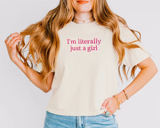 Person wearing a white t-shirt with 'I'm literally just a girl' text on a plain background