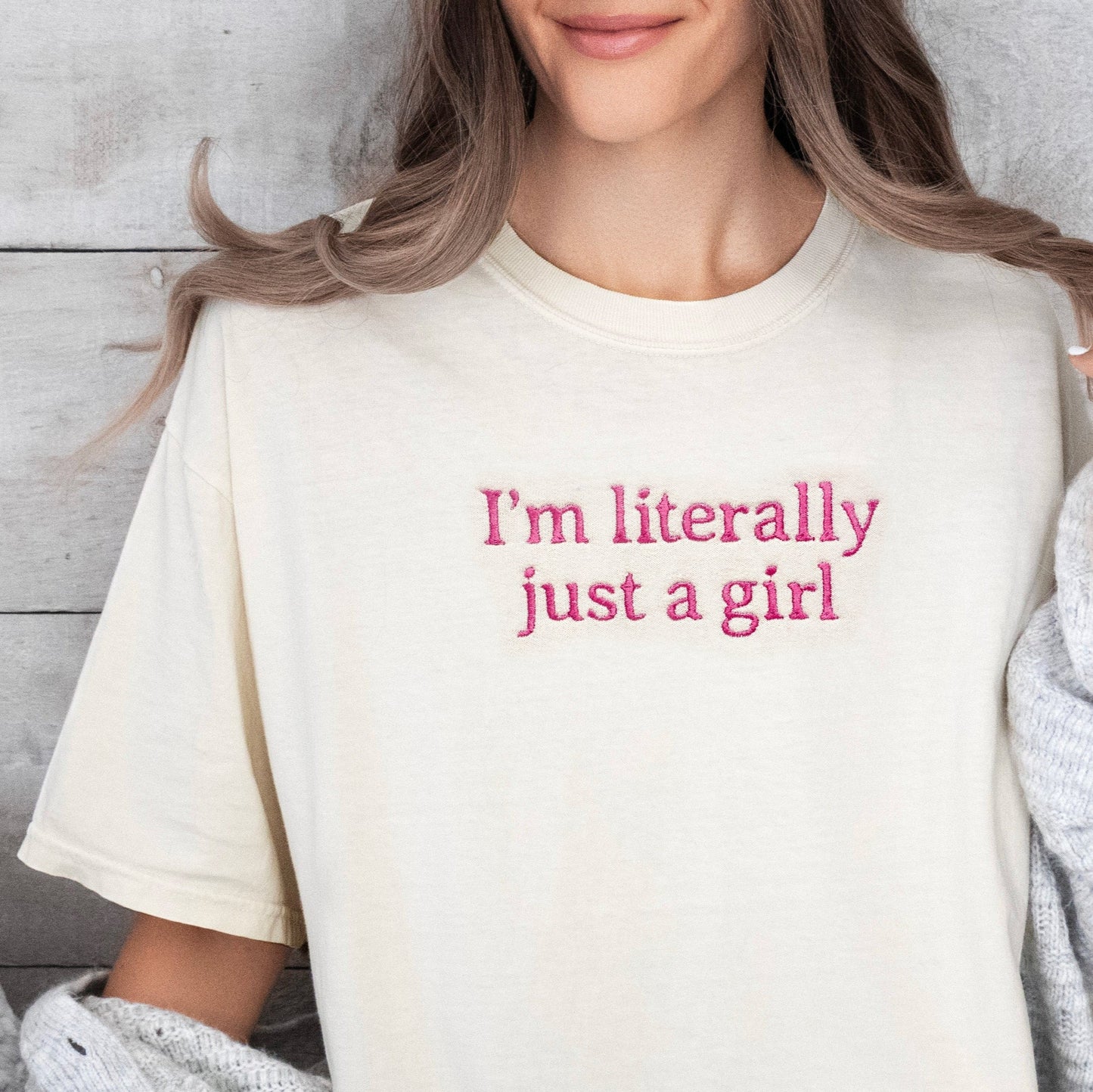 Person wearing a cream t-shirt with 'I'm literally just a girl' text, sitting on a couch.