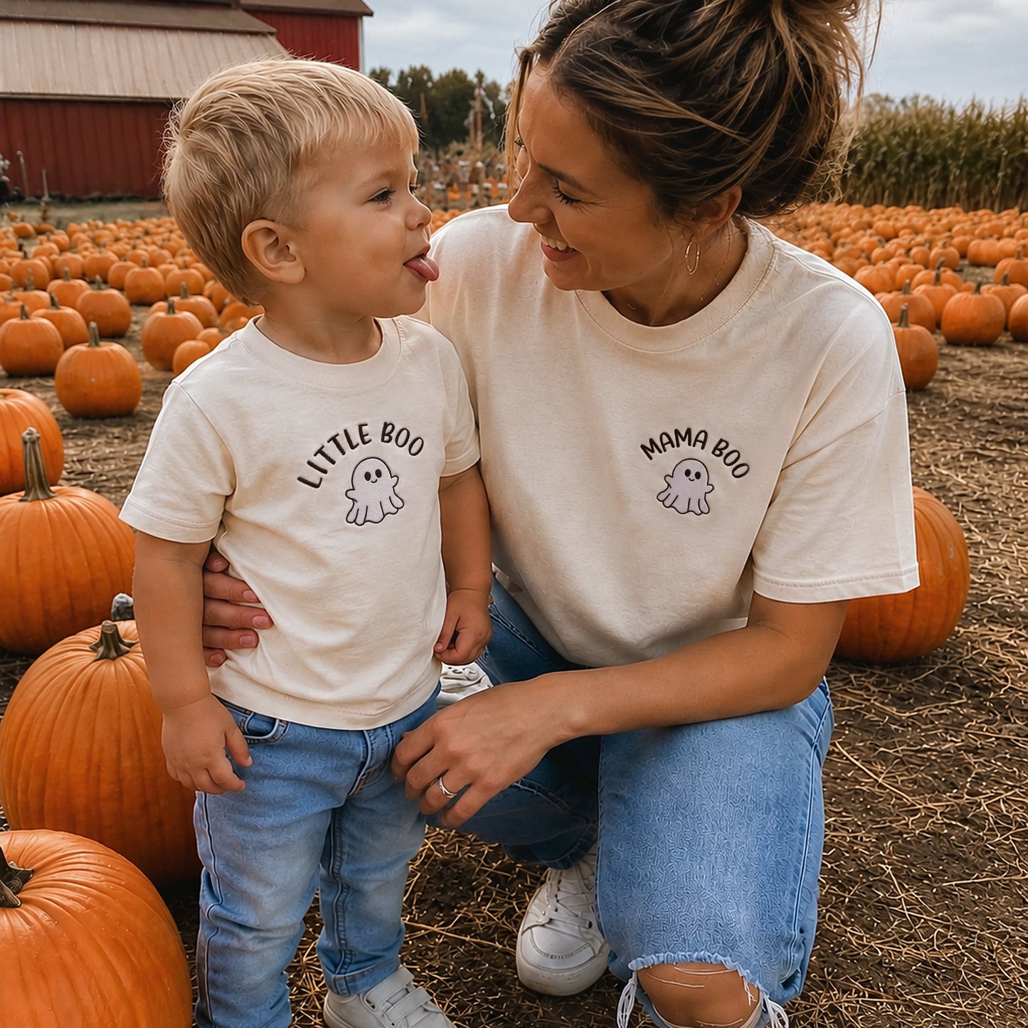 A woman and a young boy wearing matching cream graphic t-shirts with 'LITTLE BOo' and 'MOMMA BOo' text, posing together in a pumpkin field.