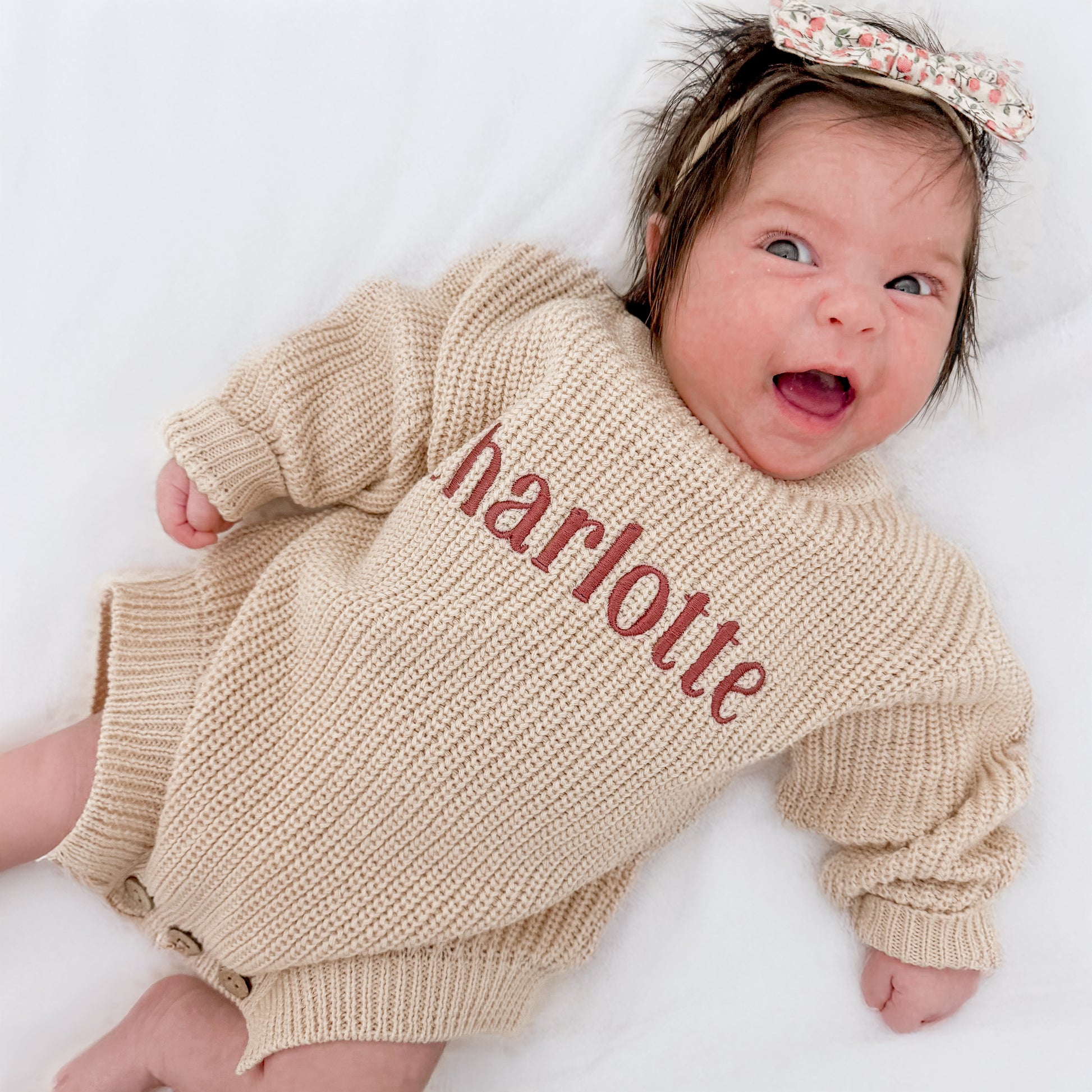 Baby wearing personalized embroidered sweater romper in neutral cotton knit