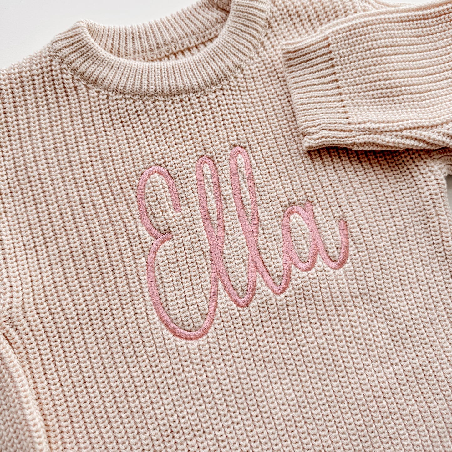Close up of personalized embroidery on cotton baby sweater romper showing detailed stitching